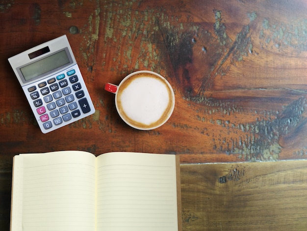 An image depicting a calculator and various tax forms, set on top of a wooden table with a cup of coffee beside it, illustrating the financial planning needed to maximize Dependent Care FSA benefits.
