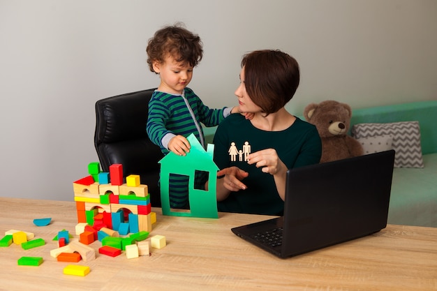 A parent reading a financial document while their child plays with building blocks nearby, symbolizing the balancing act of work, family, and financial planning within the context of the Dependent Care FSA.