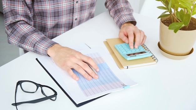 A person using a calculator and reviewing financial documents, illustrating the process of evaluating whether refinancing is the right choice.