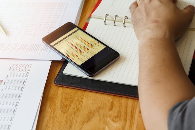 A person using a budget planning app on their smartphone to track expenses and income. The app interface is clean and modern, with colorful charts showing expense categories.