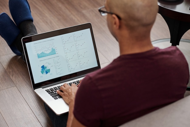 A person using a laptop to compare different high-yield savings accounts online, with charts and data highlighting APYs, fees, and other relevant account features.