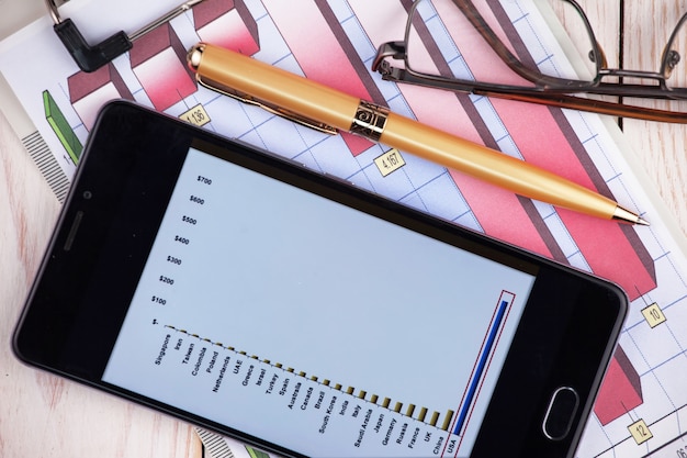A close-up shot of a calculator and pen resting on a financial document showing growth charts and investment projections for a 529 plan, emphasizing the strategic calculation and planning involved.