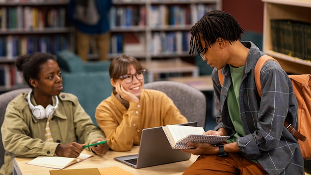 A diverse group of college students studying together in a library, surrounded by books and laptops, representing the qualified education expenses that a 529 plan can cover for various students.