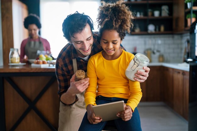 A family using a mobile budgeting app on a tablet, discussing their monthly expenses and savings goals with smiles and nods of agreement.