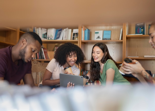A diverse group of college students collaborating on a project around a table in a modern study area, with laptops, books, and smiling faces indicating engagement and teamwork.