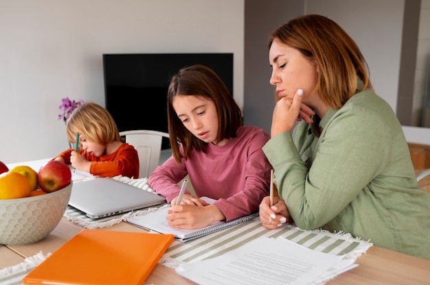 A young woman confidently filling out a scholarship application form at her desk, with a focused expression and a supportive family member offering encouragement.