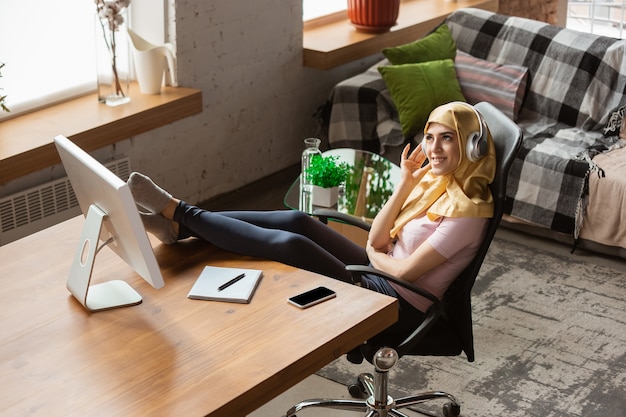 A modern home office setup with a high-quality laptop, ergonomic chair, noise-canceling headphones, and a stable internet connection. The scene emphasizes the necessary technology for online learning.