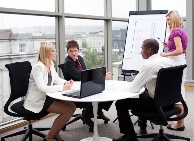 A student confidently presenting a project to a team of professionals in a boardroom. The atmosphere is professional yet supportive.