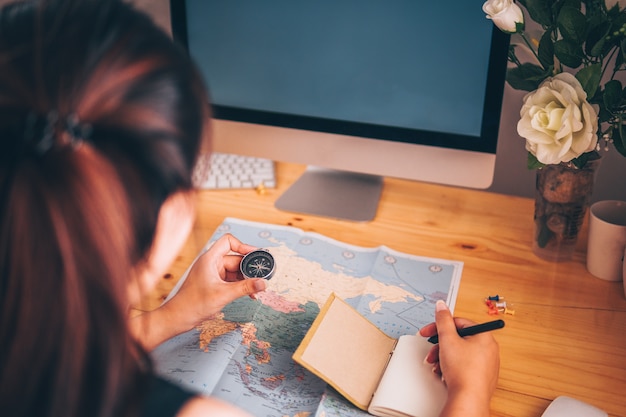 A student sits at a table, planning out her gap year using a calendar and world map.