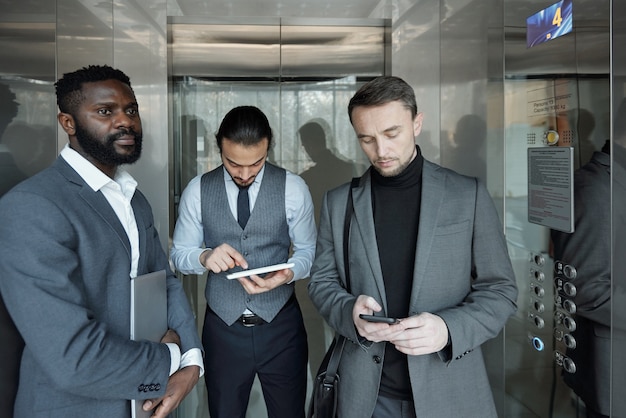 A diverse group of professionals in a modern office setting, some with visible digital badges displayed on their laptops, signifying their microcredentials.