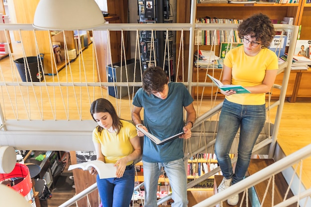 A college campus scene with students walking between buildings, studying in the library, and participating in lab experiments, showcasing different academic departments and learning environments.