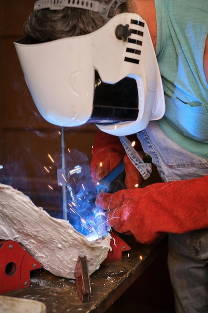 A close-up shot of a student in a welding class, wearing protective gear and expertly welding metal pieces together. Show the focus required and skill being developed.