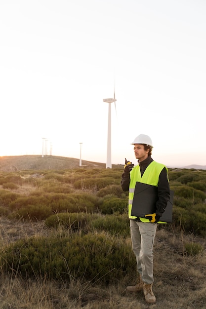 A technician working on a wind turbine, high above the ground, with a scenic landscape in the background. Show the scale and importance of renewable energy jobs.