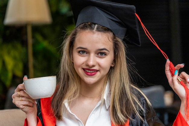 A young student smiling at a graduation ceremony, adorned with honors regalia and cap, holding a diploma, symbolizing successful completion of education and realizing the financial and academic advantages.