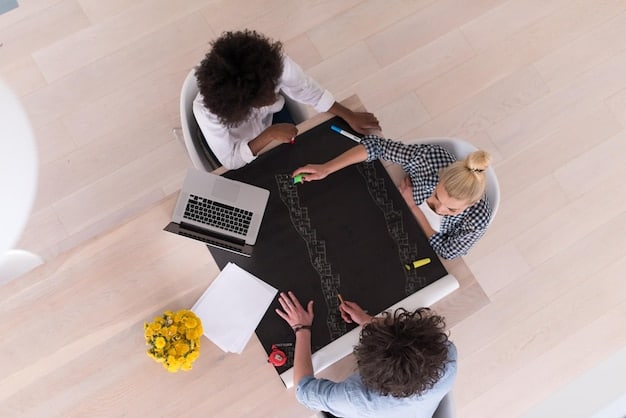 A bird's eye view of a diverse group of people collaborating on financial planning documents and a laptop in a bright office setting.