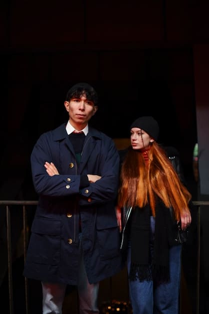 Do Do-hee (Kim Yoo-jung) and Jeong Gu-won (Song Kang) stand side-by-side with dramatic lighting in My Demon, she in a flowing black gown with lace details and he in a sharply tailored dark suit, accentuated with silver accessories. The background is a dimly lit, opulent hall.